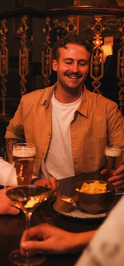 Gast lacht aan tafel met biertjes en chips in gezellige restaurantsetting, restaurant De Gribus dichtbij Voorthuizen